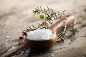 White bath salt on wooden spoon, shallow focus